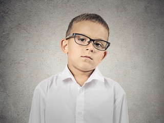 Boy with judgmental face expression on grey wall background 