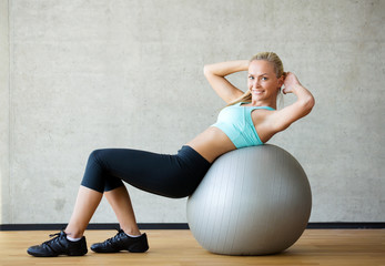 Fototapeta na wymiar smiling woman with exercise ball in gym