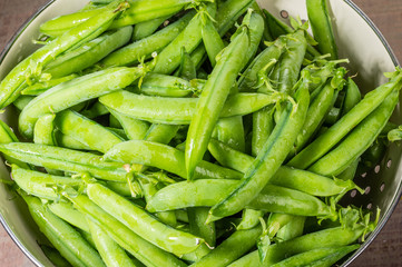 Fresh green pea pods in a bowl