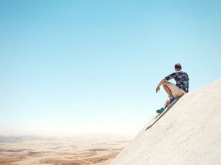 Young man sitting on a peak and desert