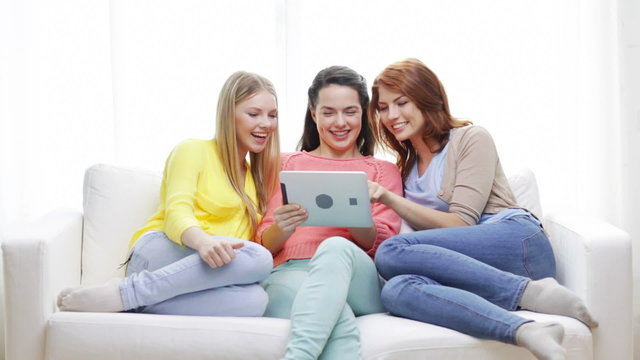 two smiling teenage girls with tablet pc at home