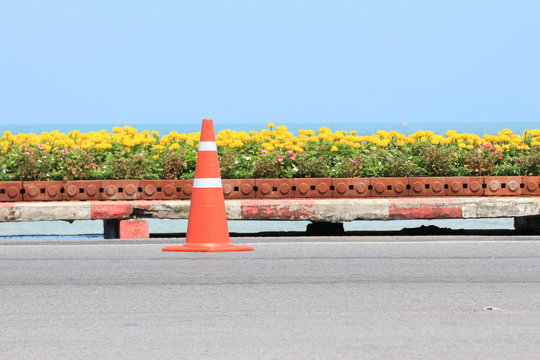 Traffic Cone On Road With Flower And Seascape Background