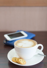 Cup of coffee and biscuits on wooden board
