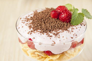 Dessert with curd cream, cereal, strawberries and chocolate.