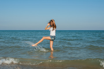 Fototapeta na wymiar young girl splashing the water in the sea