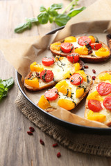 Tasty bruschetta with tomatoes on pan, on old wooden table