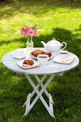 Coffee table with teacups and tasty pie in garden