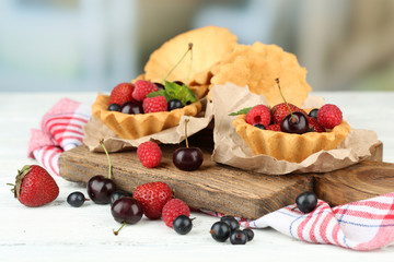 Tasty tartlets with berries on wooden table