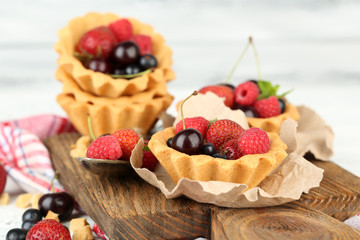 Tasty tartlets with berries on wooden table