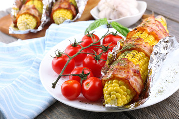 Grilled bacon wrapped corn on table, close-up