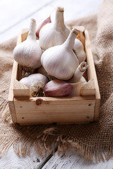 Fresh garlic in box, on wooden background