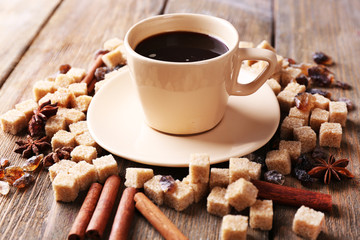 Brown sugar, spices and cup of coffee on wooden background