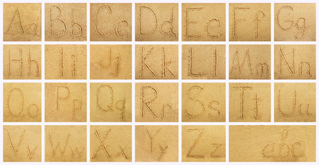 Handwritten alphabet letters on sand background