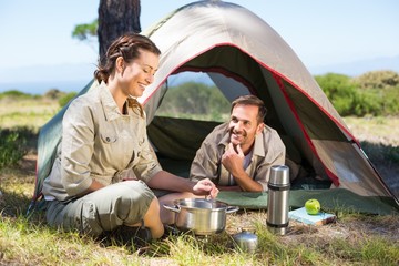 Outdoorsy couple cooking on camping stove outside tent