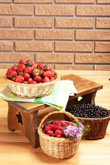 Fresh berries in baskets on wall background