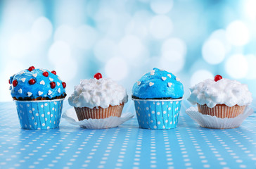 Tasty cupcakes on table, on bright background