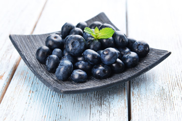 Delicious blueberries on plate on table close-up