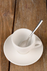 Empty cup with tea spoon on wooden background