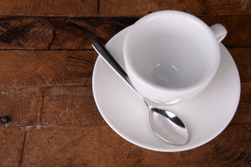 Empty cup with tea spoon on wooden background
