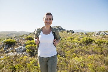 Naklejka premium Pretty hiker smiling at camera on mountain terrain