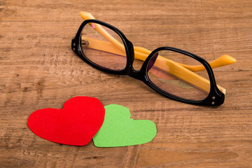 Fototapeta na wymiar eyeglasses with decorative hearts on wooden background
