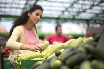 Obraz premium Pretty young woman buying vegetables on the market
