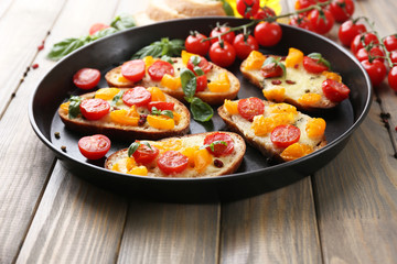 Tasty bruschetta with tomatoes on pan, on old wooden table