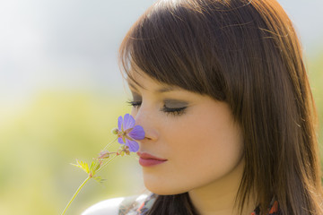 Beautiful meditative girl sniffing a flower. Beauty of nature.