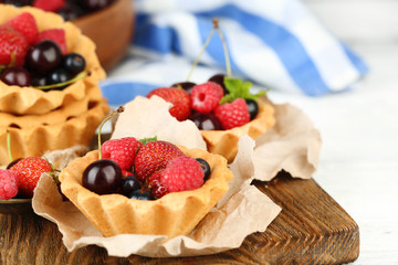 Tasty tartlets with berries on wooden table