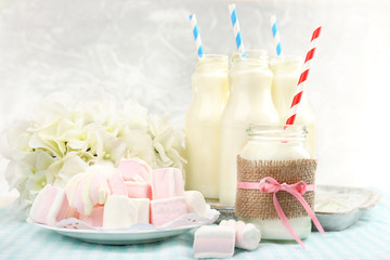 Milk in bottles with paper straws on table