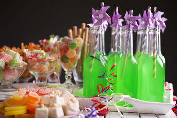 Obraz na płótnie Canvas Bottles of drink with straw and sweets on dark background