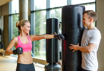smiling woman with personal trainer boxing in gym