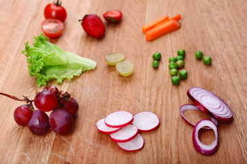 Different slices of vegetables and berries on wooden table