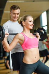 smiling man and woman with barbell in gym