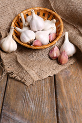 Fresh garlic in wicker basket, on wooden background