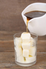 Iced coffee with milky ice cubes in glass on wooden background