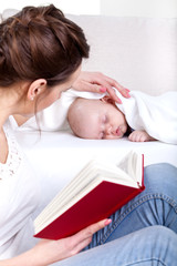 Mother reading beside sleeping baby