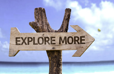 Explore More wooden sign with a beach on background