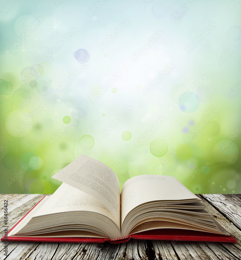 Wall mural Open book on table and green blur background