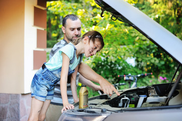 Father teaching his daughter to change motor oil in the car