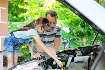 Father teaching his daughter to change motor oil in the car