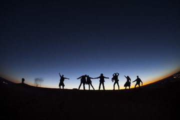 Fototapeta na wymiar Group of happy people on top of a mountain in the Sahara desert,