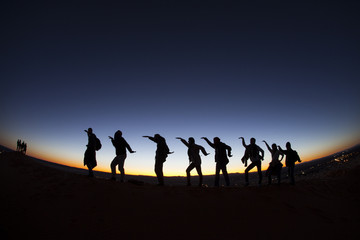 Group of happy people on top of a mountain in the Sahara desert,