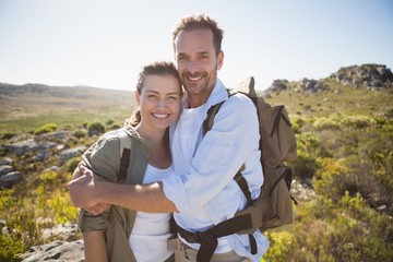 Hiking couple embracing and smiling at camera