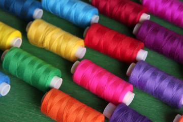 Multicolor sewing threads on wooden background