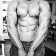 Naklejka premium Shirtless muscular man flexing muscles in gym