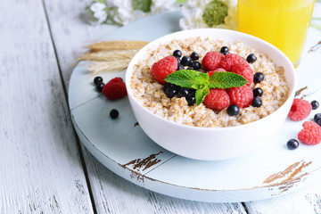 Tasty oatmeal with berries on table close-up