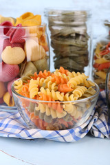 Colorful pasta in glass jars on wooden background
