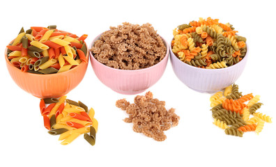 Assortment of colorful pasta in color bowls isolated on white