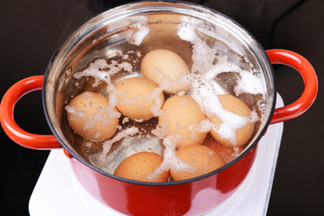 Eggs in boiling water in pan on electric hob